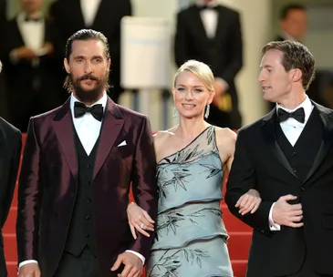 Naomi Watts, flanked by two men in tuxedos, pose on the red carpet at Cannes for "The Sea of Trees" premiere.