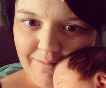 A close-up of a woman holding a sleeping baby, capturing a tender moment.