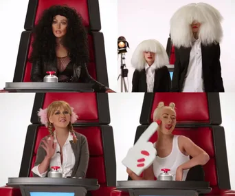 In "The Voice" chairs, a woman imitates famous singers with distinct wigs and outfits, sitting at red buttons.