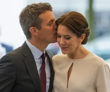 Prince Frederik kisses Princess Mary on the forehead during their tour of Germany, showcasing their affection.