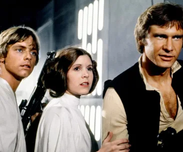 Luke Skywalker, Princess Leia, and Han Solo stand together, looking intently in "Star Wars: A New Hope."
