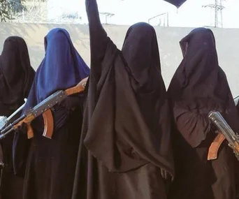 Women in black robes and headscarves, some with rifles, standing in a group with one raising an arm.