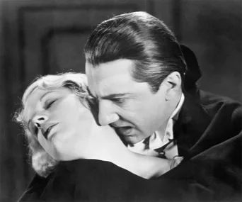 A vampire leans in to bite a woman's neck in a dramatic black-and-white scene.