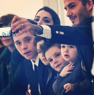 People taking a selfie, including a man and children, all looking at the camera with smiles and curiosity.