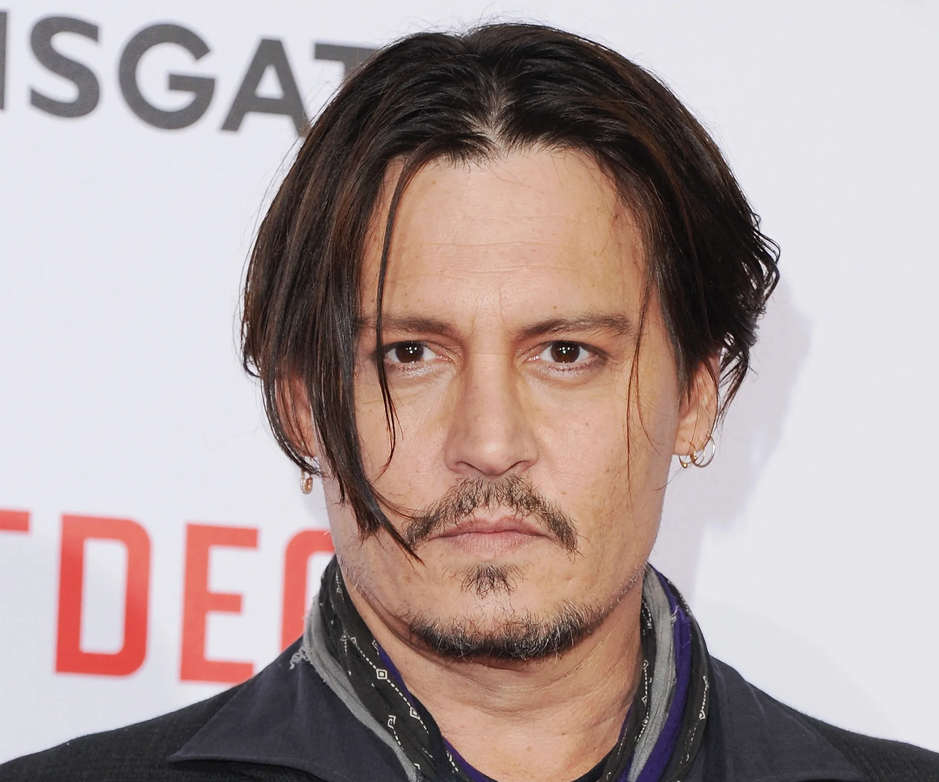 A person with medium-length hair and facial hair, wearing a scarf, at a formal event.