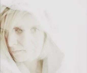 A woman with a hooded white robe, semi-transparent in a ghostly artistic overlay.
