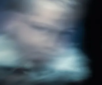 Blurred, ghostly figure with indistinct features against a dark, misty background.