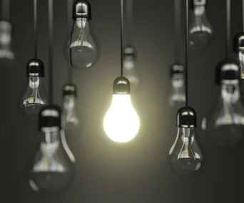 Alt text: "Brightly lit bulb among several dim ones, symbolizing discovery or innovation."