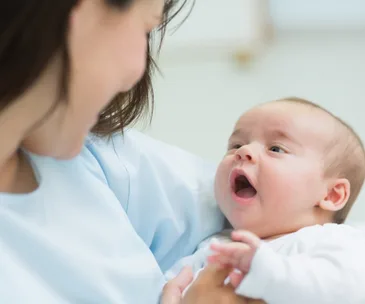 Mother holding and smiling at her newborn baby.
