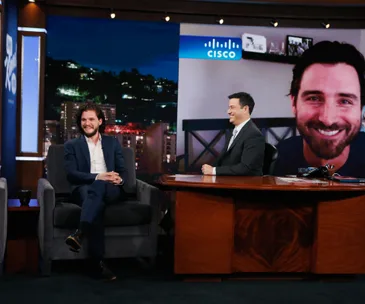 Kit Harington on a talk show set, smiling with host. Past Jon Snow impersonations might be discussed.