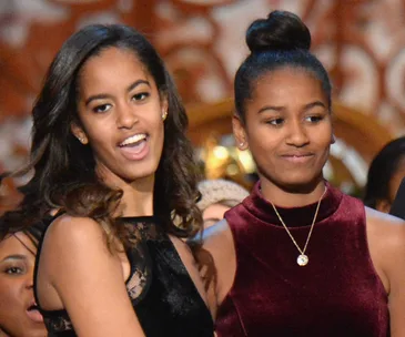 Two young women smiling and standing together at a formal event.