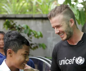 David Beckham smiles with a child during a UNICEF visit to Cambodia.