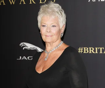 A person with short hair attends a formal event wearing an elegant black dress and diamond necklace.
