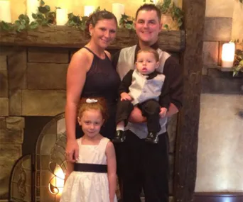 Family of four posing in front of a stone fireplace, smiling together.