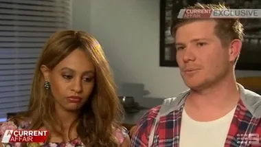 Couple sitting together during an interview on a TV program, looking serious and solemn.