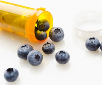 Blueberries spilling from an open prescription bottle, symbolizing unconventional wellness trends.