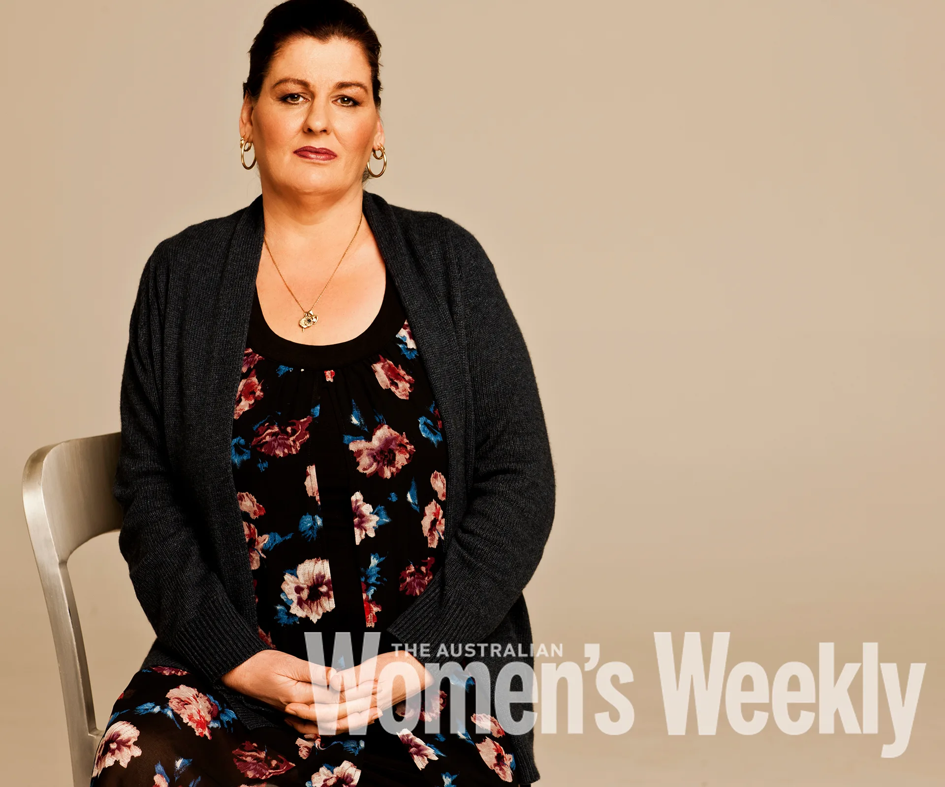 A woman seated on a chair, wearing a floral dress and cardigan, featured in The Australian Women's Weekly.