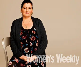 A woman seated on a chair, wearing a floral dress and cardigan, featured in The Australian Women's Weekly.