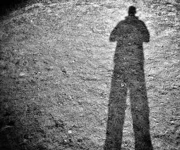 Shadow of a person's silhouette cast on the ground, suggesting secrecy or hidden identity.