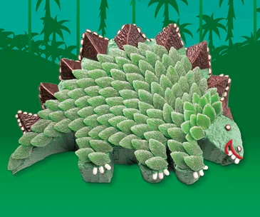 Green stegosaurus cake made of spearmint leaves and chocolate, set against a jungle-themed background.