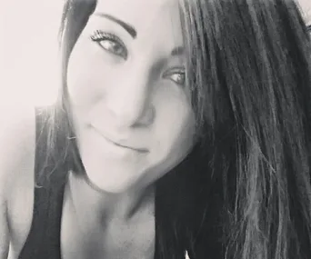 Black and white close-up of a woman smiling with long hair, partially in shadow.