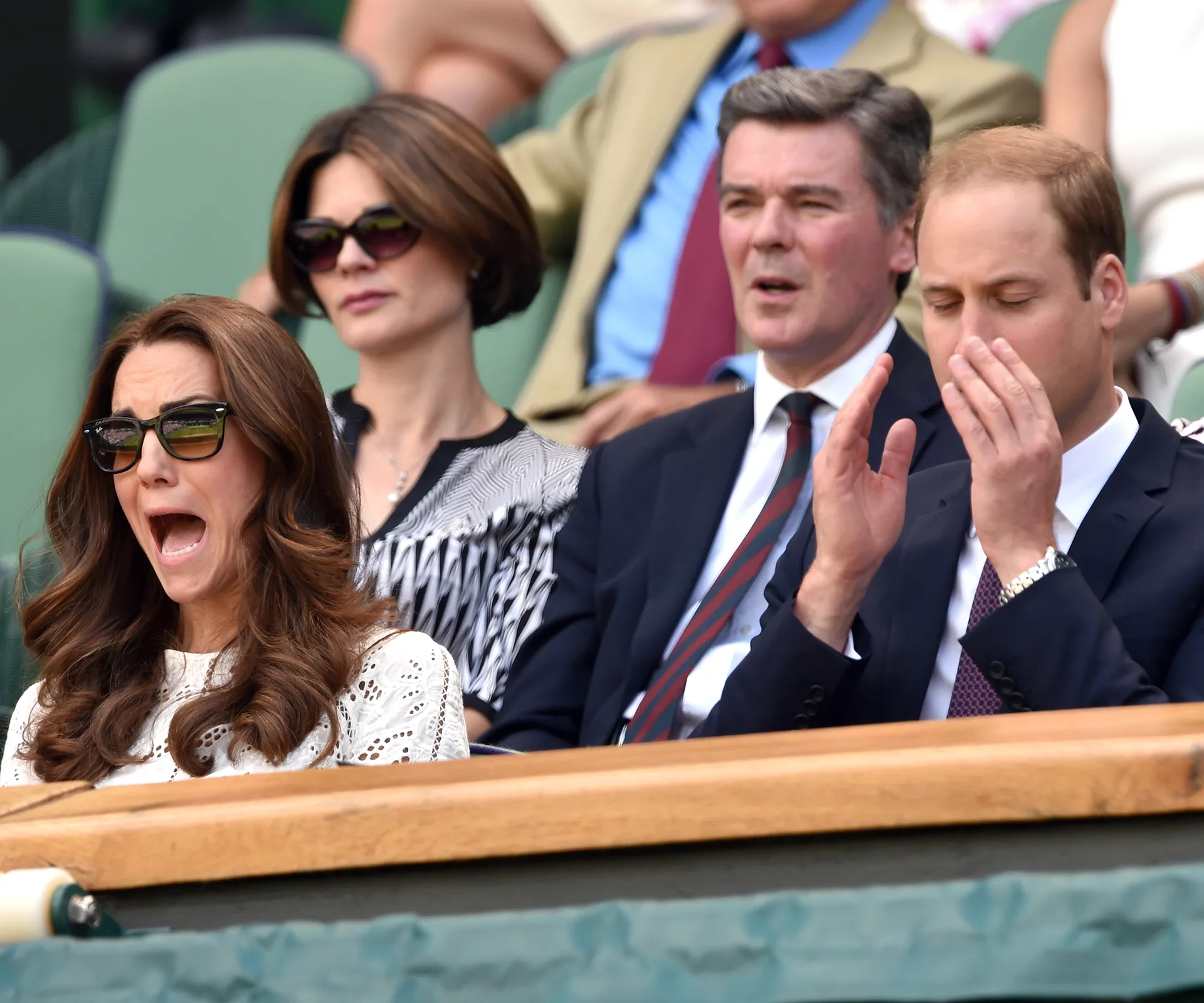 "Two people at Wimbledon, one cheering with mouth open, the other clapping with eyes closed, seated in the stands."