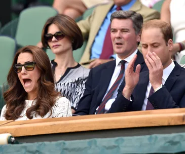 "Two people at Wimbledon, one cheering with mouth open, the other clapping with eyes closed, seated in the stands."