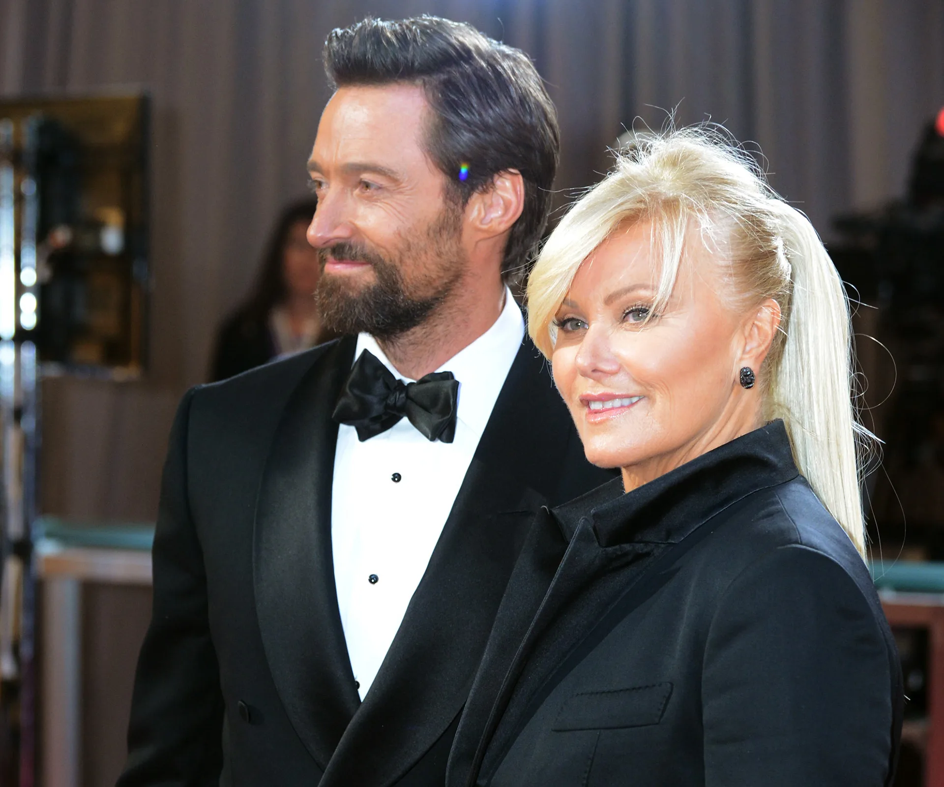 Couple in formal attire smiling on a red carpet event.