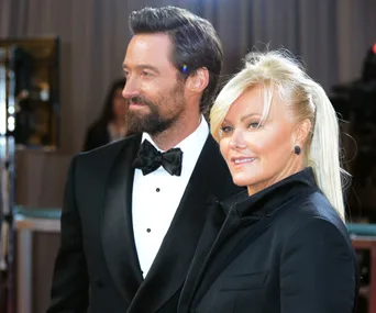 Couple in formal attire smiling on a red carpet event.