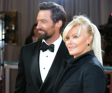 Couple in formal attire smiling on a red carpet event.