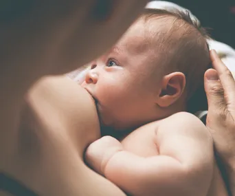 A baby breastfeeding while being held, highlighting nurturing and maternal care.
