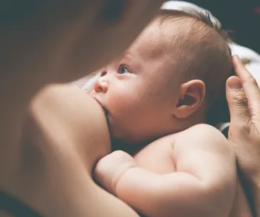 A baby breastfeeding while being held, highlighting nurturing and maternal care.