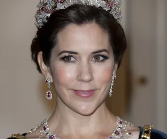 A woman wearing a sparkling tiara and matching jewelry, smiling at the camera.