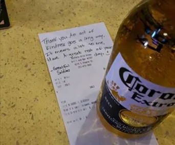 Bottle of Corona beer on a bar with a handwritten note saying "Thank you. An act of kindness goes a long way."