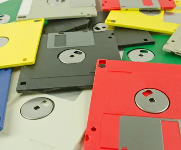 Pile of colorful floppy disks, including red, yellow, black, and gray, used for data storage in the past.