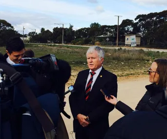 Police spokesperson giving a statement outdoors surrounded by media and cameras.