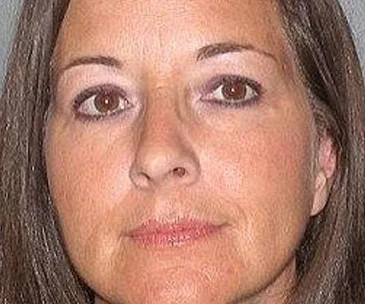 A woman with long brown hair and serious expression. Her face is centered in the image.