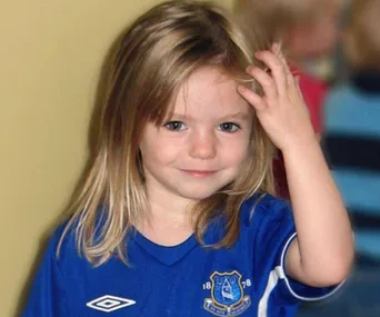 Young girl in an Everton soccer jersey, smiling and touching her hair.