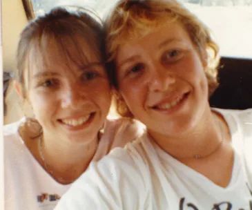 Two smiling people taking a close-up photo together inside a car.