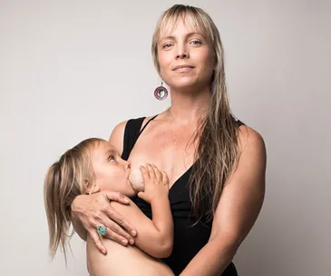 Mother confidently breastfeeds her young child, both looking content and serene, showcasing nurturing and bonding.