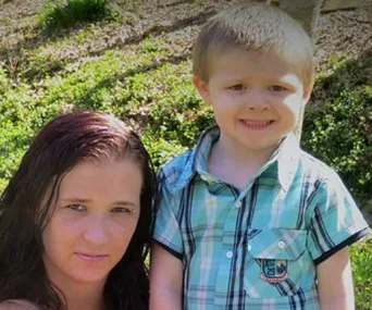 A woman with brown hair and a young boy in a plaid shirt standing together outdoors.