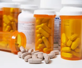 Prescription bottles with scattered pills on a table.
