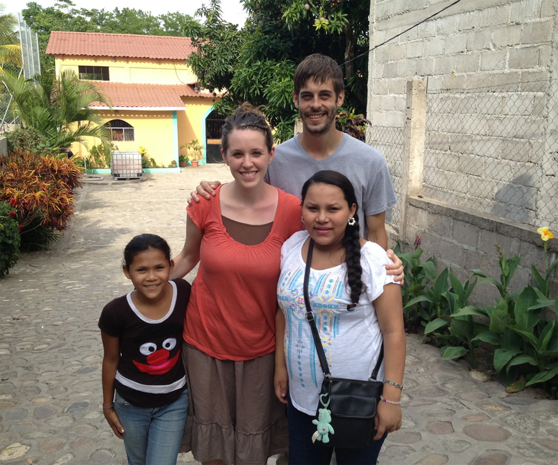 Family posing outside a house in a garden setting.