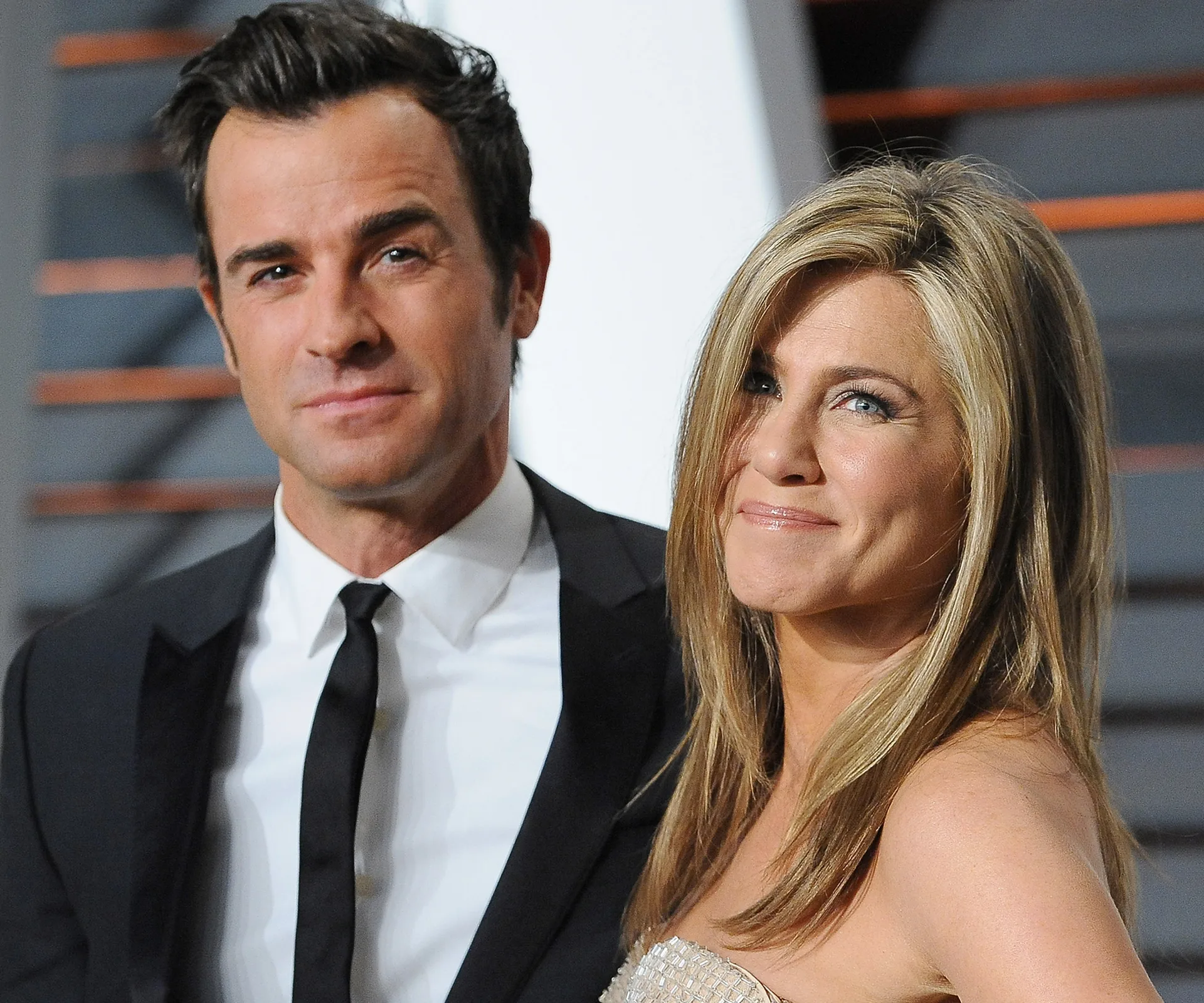 A couple posing together on a red carpet, dressed formally and smiling at an event.