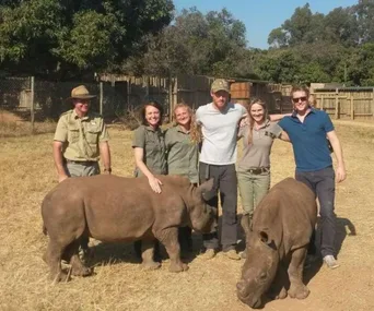 Group posing with rhinos in a wildlife reserve in South Africa.