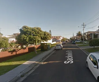 Street view of Sackville St, residential area with parked cars, trees, and a clear sky.