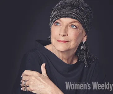 A woman in a black headscarf and earrings gazes upward thoughtfully against a dark background.