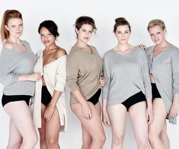 Group of five models wearing casual tops and black shorts, standing confidently against a plain background.