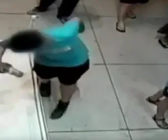 A boy accidentally loses balance near a painting in a crowded gallery, about to inadvertently damage it.
