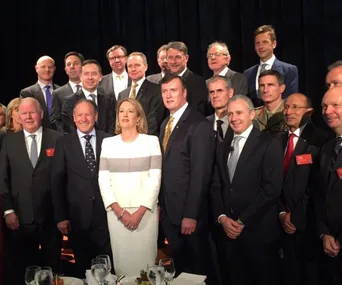A group of executives, mostly men in suits, standing together for a photo at a gender equality event.